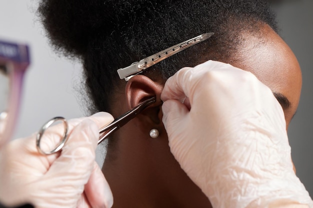 Gros plan sur l'oreille d'une femme percée à l'oreille pour le traitement de la douleur à un endroit sur son corps par un médecin chinois