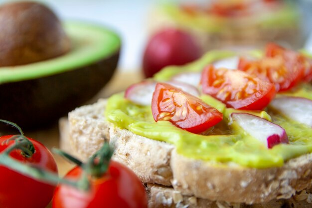 Gros plan de pain grillé avec avocat, radis et tomate