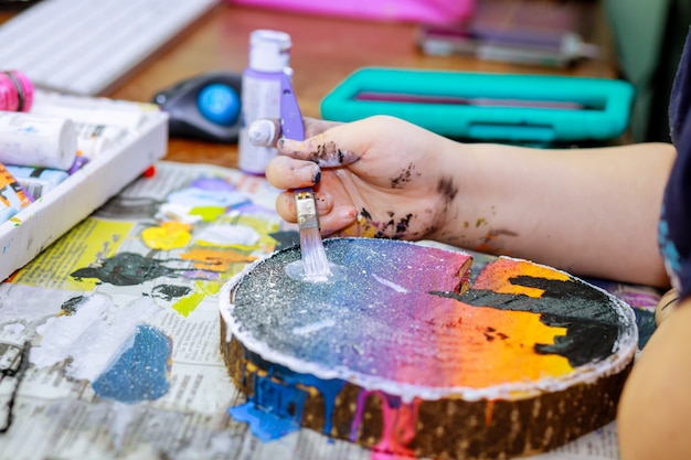 Gros plan d'une palette en bois avec de la peinture acrylique et un pinceau en mains d'artiste sur bois