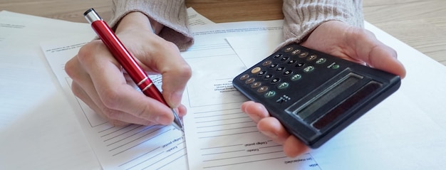 Gros plan panoramique de mains féminines comptant avec une calculatrice et prenant des notes