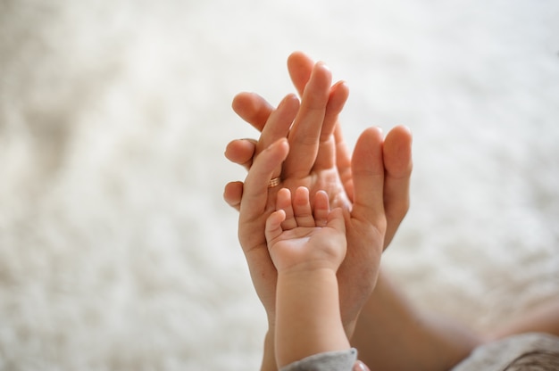 Gros plan des parents et bébé joignent les mains