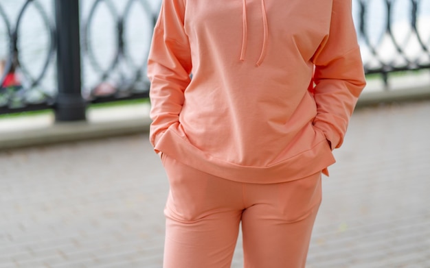 Photo gros plan sur une partie du corps d'une femme debout sur un talus dans la ville corps d'une femme méconnaissable dans des vêtements décontractés de couleur pêche