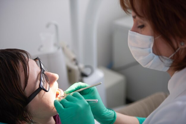 Gros plan d'une patiente chez le dentiste attendant d'être vérifiée avec la femme médecin en arrière-plan