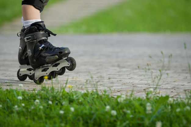 Gros plan sur le patin à roues alignées Les jambes du patineur à roulettes dans le parc Les jambes du garçon en patins à roues alignées