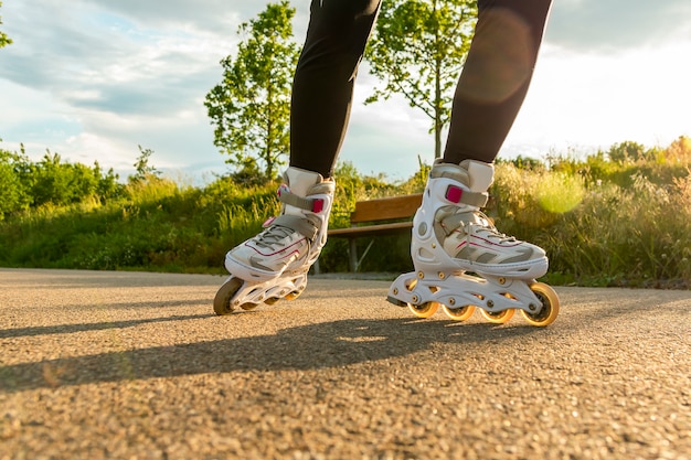 Gros plan de patins à roues alignées blanches sur le chemin. Jambes de femme avec patins à roues alignées à journée ensoleillée.