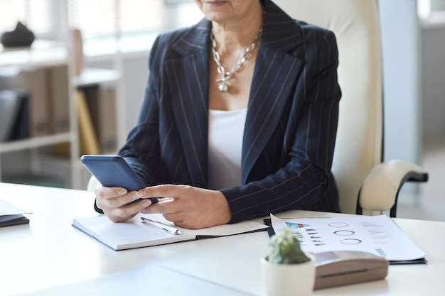 Gros plan d'une patronne utilisant un smartphone sur le lieu de travail dans l'espace de copie de bureau