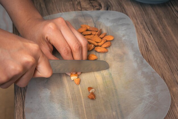 Gros plan d'une personne avec un couteau de cuisine coupant des amandes dans sa cuisine