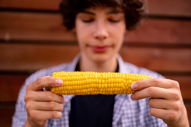 Gros plan personne mangeant et mordant des concepts d'aliments de rue de maïs préparés chauds cuits