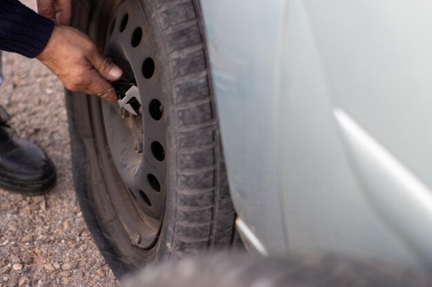 Gros plan sur une personne méconnaissable qui change un pneu de voiture crevé après un accident de voiture