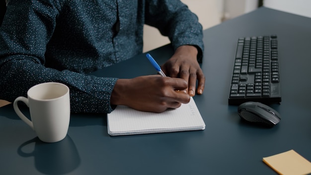 Gros Plan D'une Personne Noire Afro-américaine Prenant Des Notes Sur Le Bloc-notes à L'aide D'un Stylo Mâle Adulte Mains De Re...