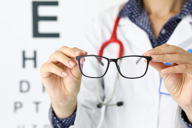 Gros plan de personne tenant des lunettes élégantes noires avec cadre parfait avec lettre sur