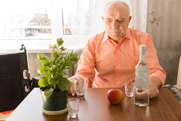 Gros plan sur des personnes âgées assises seules et buvant du vin à la table avec une pomme et une plante verte sur le dessus.