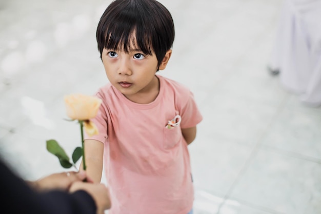 Gros plan petit garçon donne une rose jaune