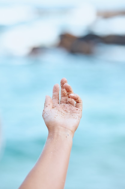 Gros plan petit grain de sable dans la main de la femme ouverte