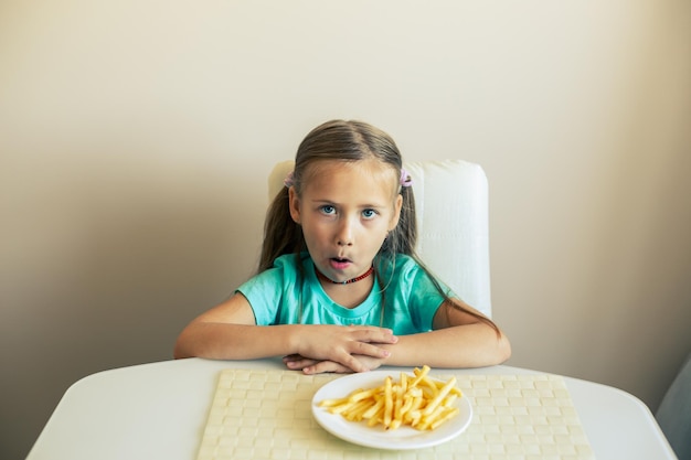 Gros plan d'une petite fille mangeant des frites à la cuisine