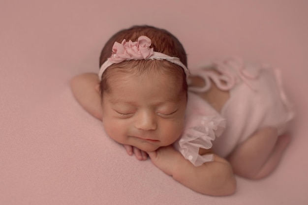 Gros plan d'une petite fille nouveau-née souriante allongée sur un tissu rose