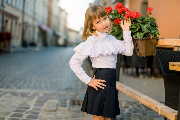 Gros plan de la petite fille de race blanche jolie blonde toucher fleur rouge