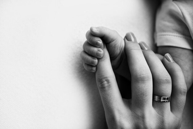 Gros plan petite main d39enfant et paume de la mère et du père Le nouveau-né a une prise ferme sur le doigt du parent après la naissance Un nouveau-né tient le doigt du papa de maman Photo en noir et blanc