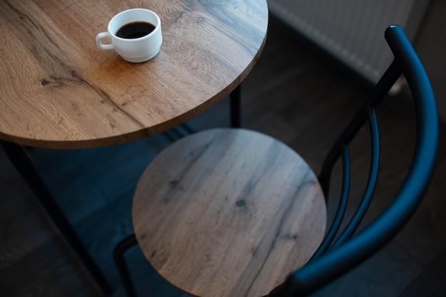 Gros plan d'une petite tasse blanche d'espresso sur le bureau en bois brun clair