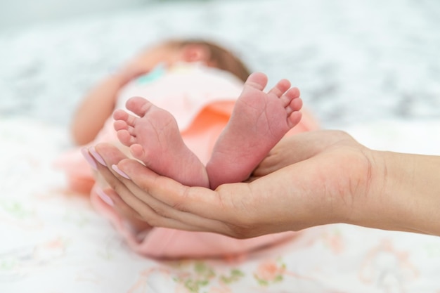 Gros plan des petites jambes d'un nouveau-né dans les mains d'une femme ou d'une mère Moments avec un enfant