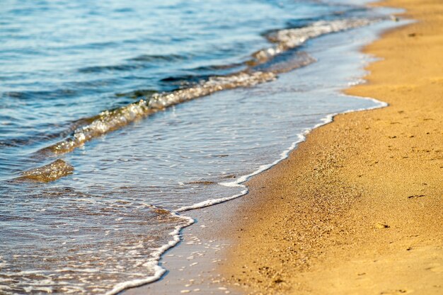 Photo gros plan de petites vagues avec de l'eau bleu clair sur une plage de sable jaune