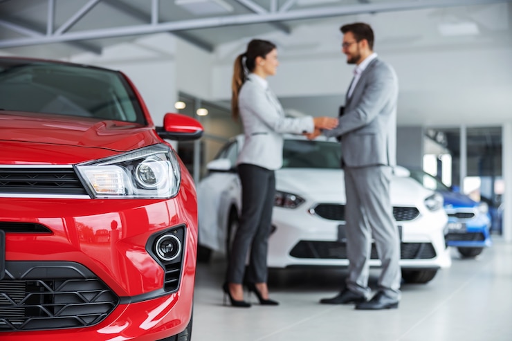 Photo gros plan des phares d'une voiture. vendeur de voiture et client se serrant la main.
