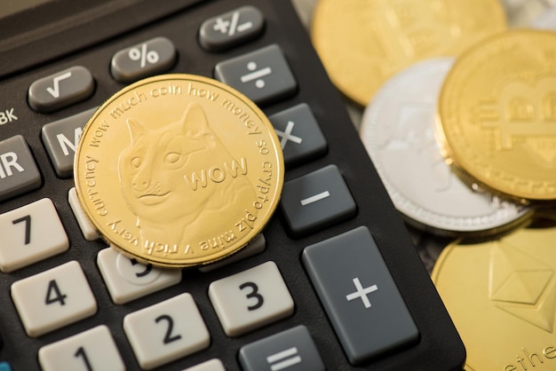 Gros plan photo de dogecoin d'or sur la calculatrice et les pièces avec des symboles de crypto-monnaie