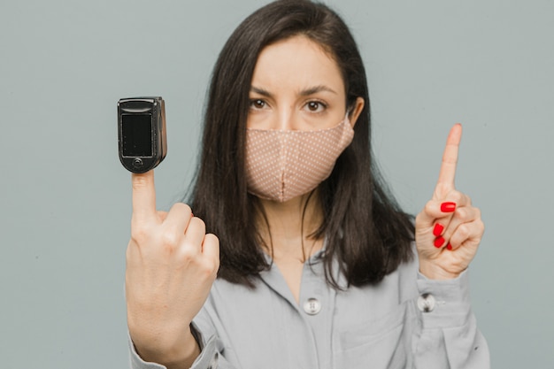 Gros plan photo femme avec oxymètre de pouls sur son doigt, vérifie sa santé