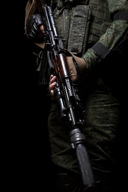 Photo gros plan photo de la main de l'homme tenant une mitrailleuse l'homme porte l'uniforme militaire