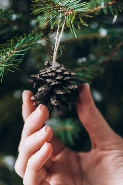 Gros plan photo de la main qui tient les boules rouges sur le sapin de Noël