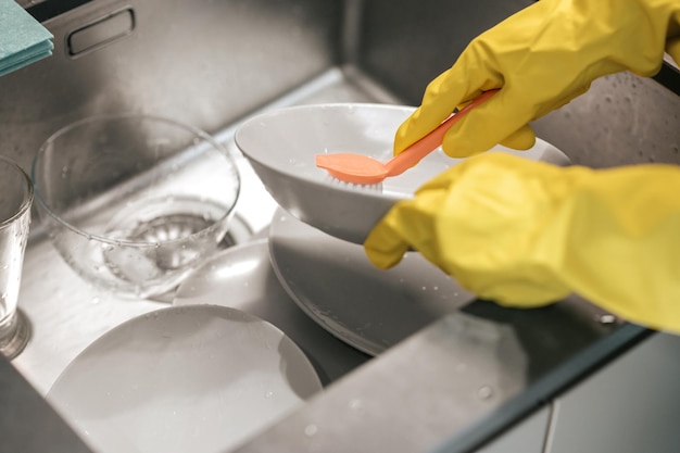 Gros plan photo de mains dans des gants pour laver la vaisselle