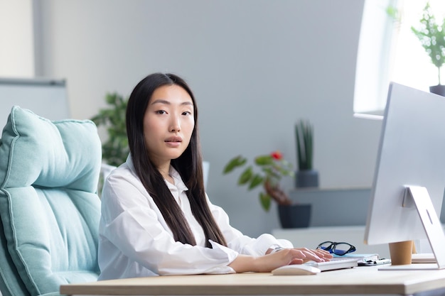 Gros plan photo portrait d'une belle jeune femme asiatique secrétaire assis au bureau à la