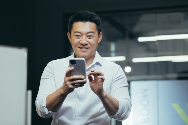 Gros plan photo portrait d'un homme d'affaires au bureau debout souriant et utilisant le téléphone