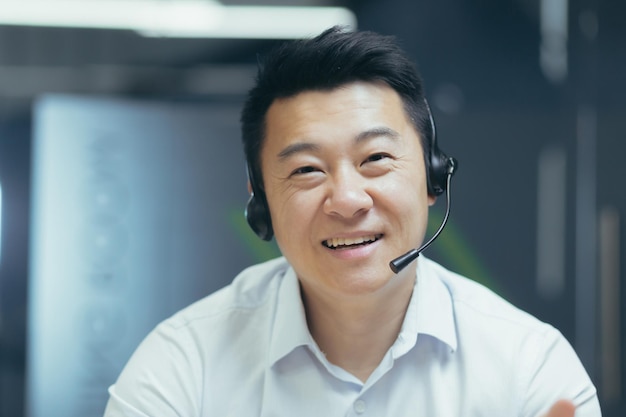 Gros plan photo portrait d'un homme asiatique avec casque d'appel vidéo travailleur de support technique souriant et regardant