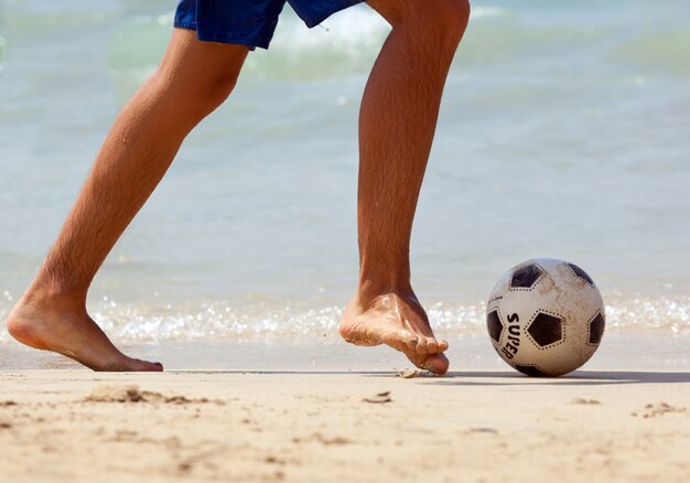 Gros plan, pied masculin, football jouant, sur, sable