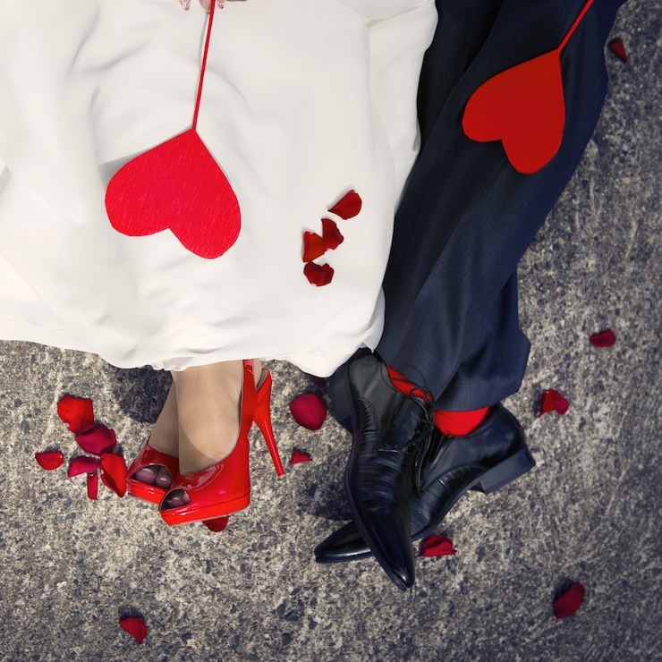 Photo gros plan des pieds amoureux et deux coeurs rouges couchés dessus.