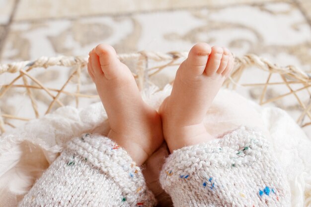 Gros plan des pieds de bébé nouveau-né sur plaid tricoté dans un panier caronculé. Doigts de bébé nouveau-né doux. Bébé. Confortable. Famille