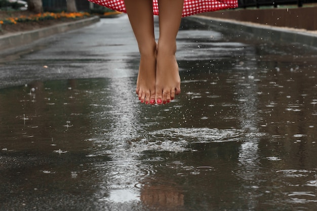 gros plan des pieds d&#39;une fille dansant dans une flaque après une pluie d&#39;été