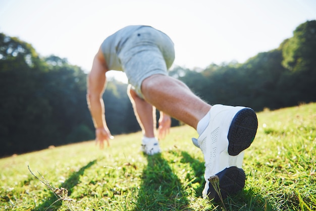 Gros plan des pieds d'un homme qui court dans l'herbe.