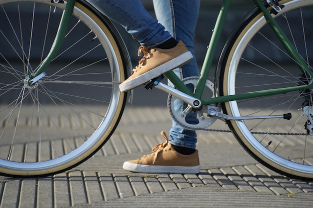 Gros plan des pieds et des roues du vélo urbain