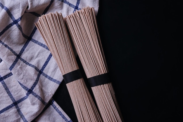 Un gros plan d'une pile de nouilles en bambou sur une serviette noire et blanche.