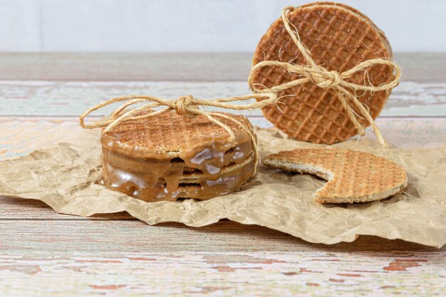 Gros plan d'une pile de stroopwafels avec un arc en sisal, à côté d'un autre biscuit avec une morsure.