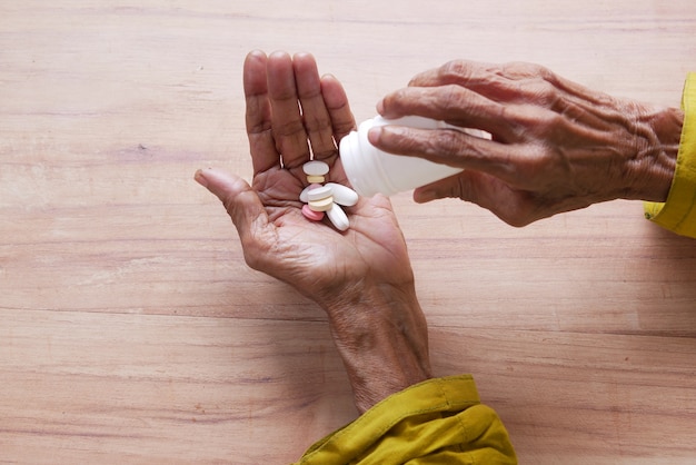 Gros plan sur des pilules et des capsules sur la main des femmes âgées