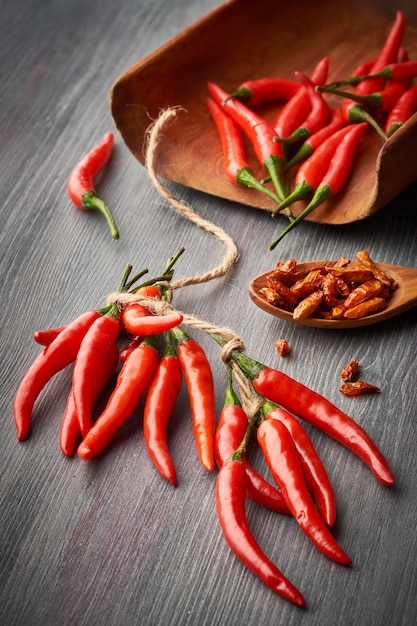 Gros plan sur les piments rouges chauds attachés avec une ficelle et une cuillère avec des poivrons séchés sur bois foncé