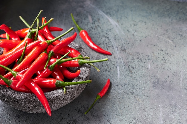 Gros plan sur les piments rouges dans un bol en pierre sur une table texturée sombre