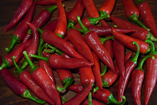 Gros plan des piments rouges frais et humides sur une table en bois