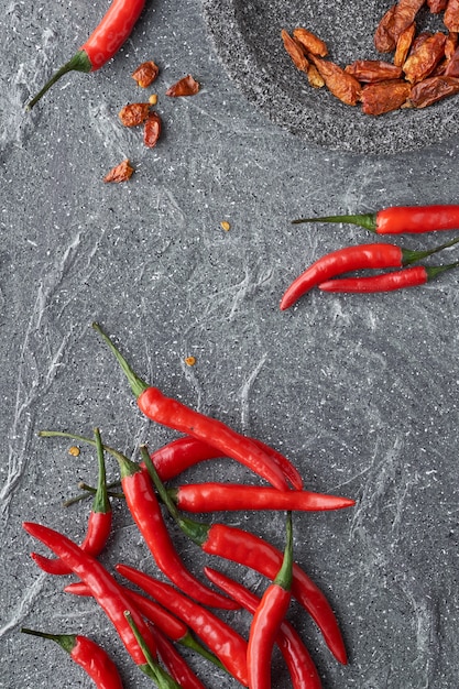 Gros plan sur les piments rouges, frais et sec, sur pierre grise, mise à plat