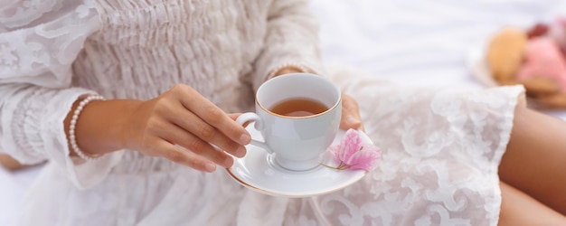 Gros plan de pique-nique au thé d'été de mains féminines avec une tasse de thé