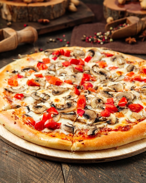 Gros plan sur la pizza aux champignons et tomates sur la table en bois