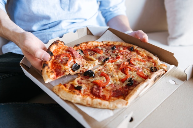 Gros plan d'une pizza en boîte sur les genoux des hommes